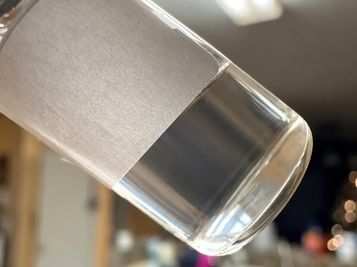 The same vial held up to the light, its liquid perfectly clear